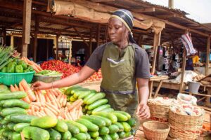Female African grocery seller standing at her stall in a market, ready to sell to customers