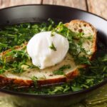 Light green soup with poached egg and bread.