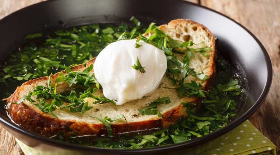 Light green soup with poached egg and bread.