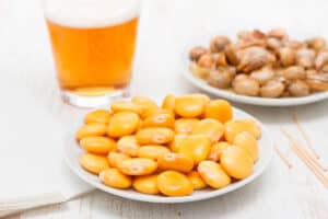 Salted lupins on a white plate next to a glass of beer.