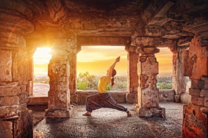 A woman doing yoga at the Hampi temple at sunrise in India.