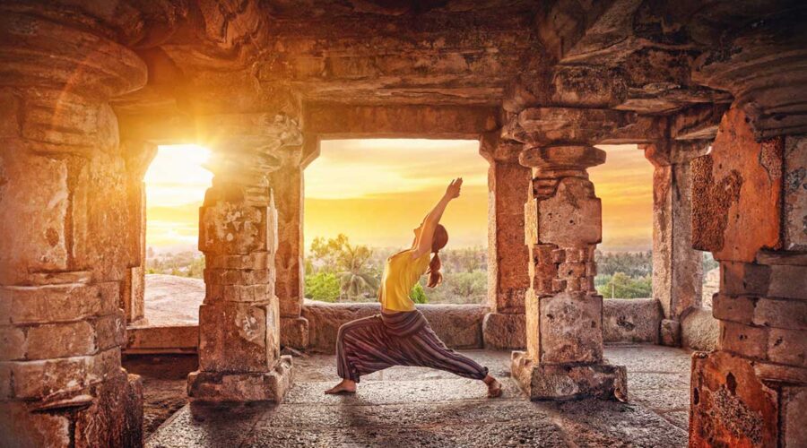 A woman doing yoga at the Hampi temple at sunrise in India.