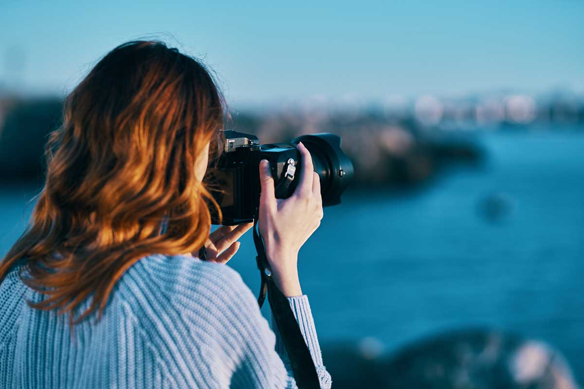 Woman with camera capturing a sea landscape.