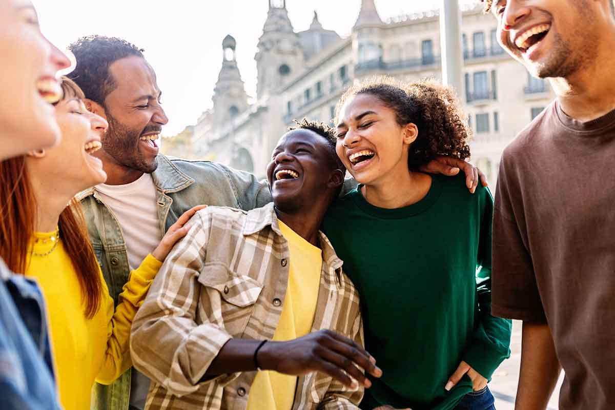 Young group of happy people having fun outdoors. Millennial diverse friends laughing enjoying travel vacation together in Barcelona.