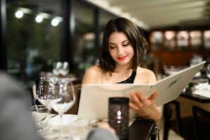 A woman reading the food menu in a french restaurant.