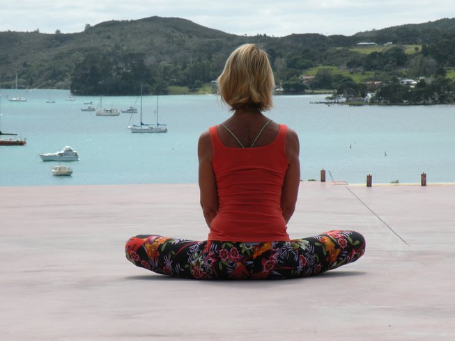 woman doing yoga with mountain and bay views on a yoga hiking retreat in New Zealand