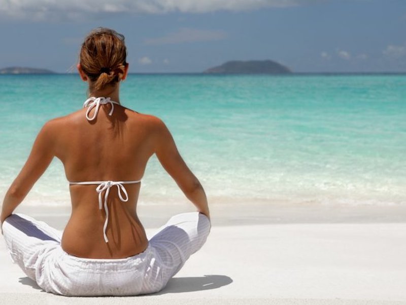 woman doing yoga on a white sand beach during a luxury wellness retreat in Anguilla