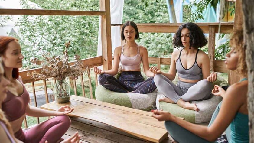 Group of women meditating in lotus pose in patio of retreat center in the Caribbean.