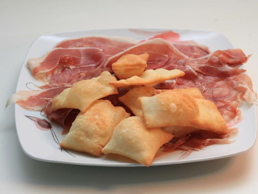 a plate of food in Bologna showcasing gnocco fritto with prosciutto