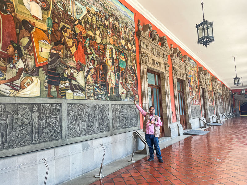 tour guide pointing to some of the top murals in Mexico City at the National Palace