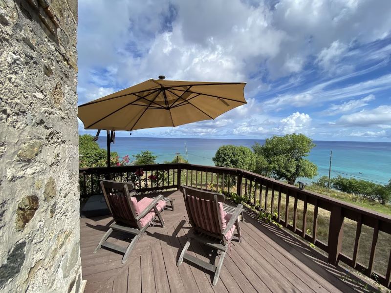 balcony with wooden chairs overlooking the Caribbean Sea at the vegan-friendly Feather Leaf Inn