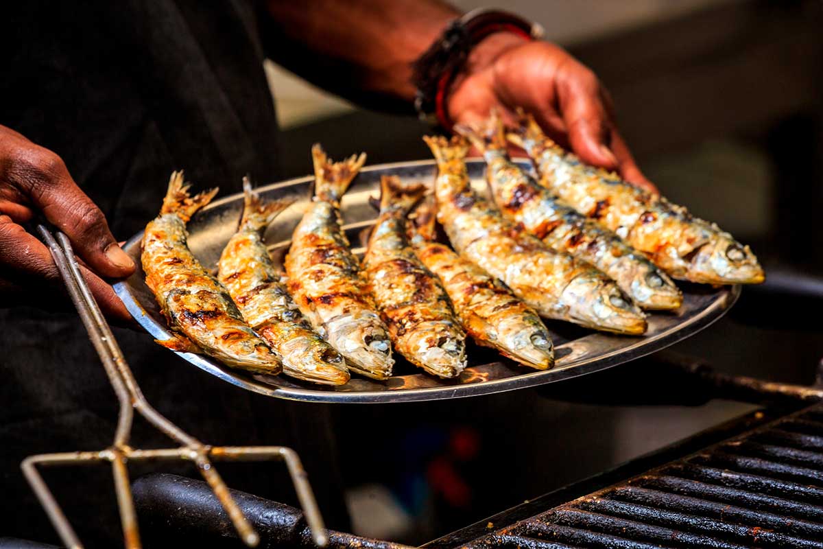 A man holding a silver tray with grilled sardines in Istria