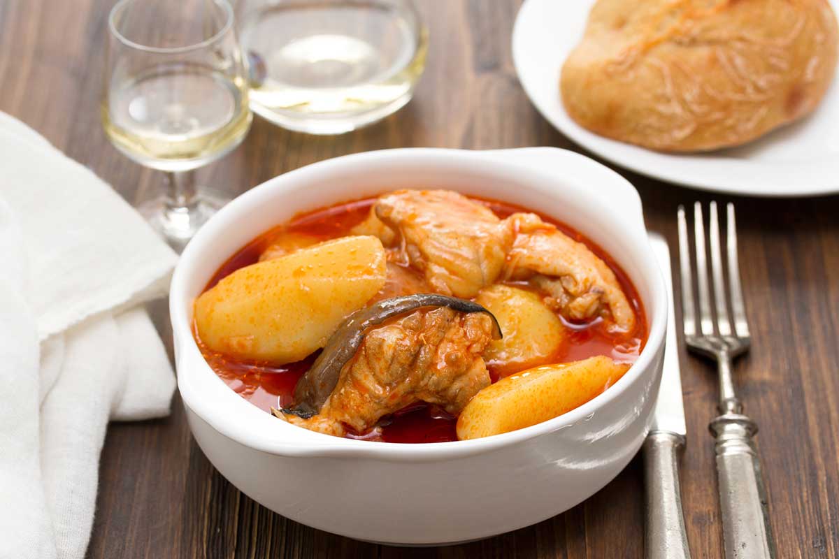 Fish stew on white bowl on wooden background.
