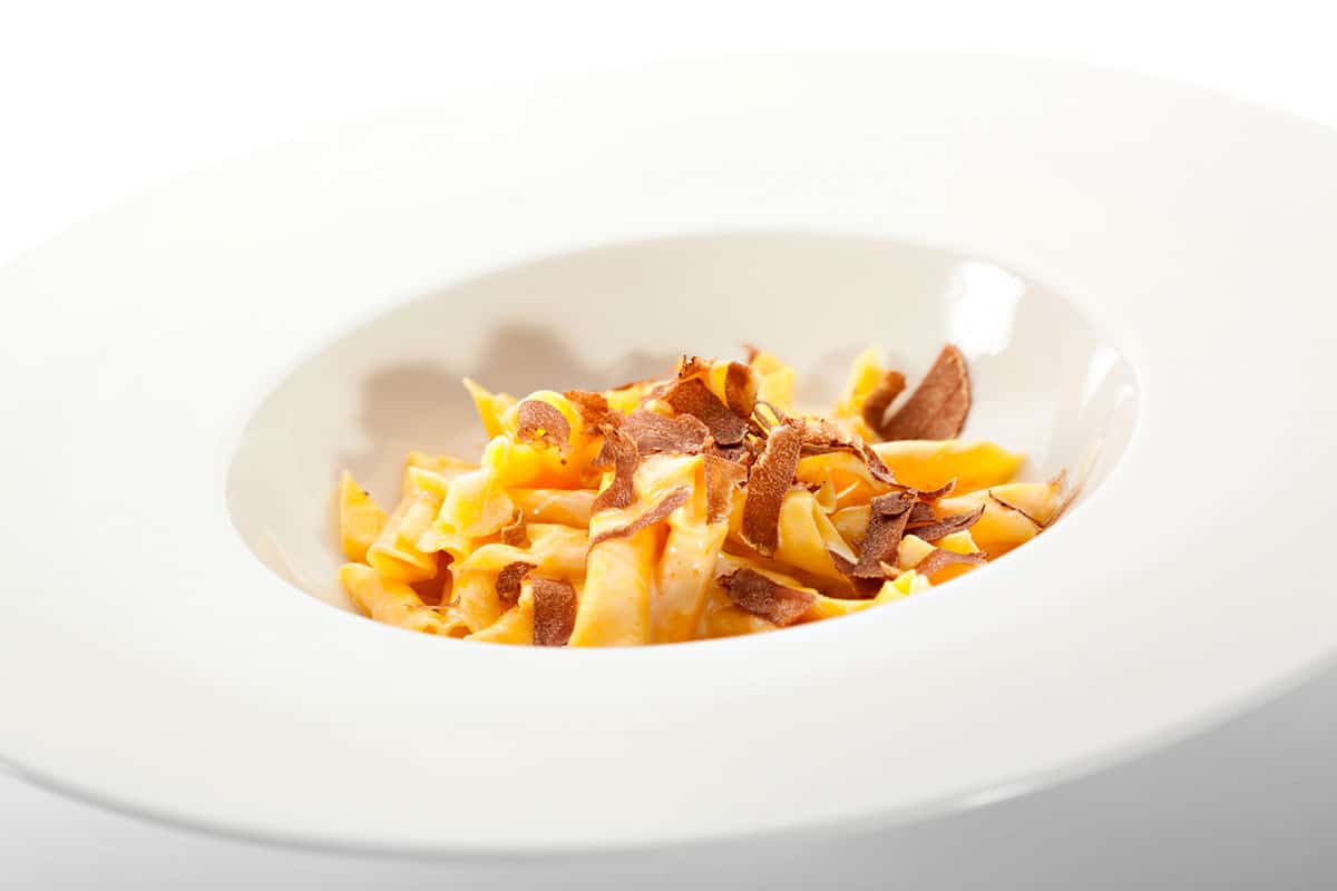 A bowl of pasta with truffle shavings.