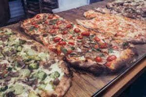 Close up on a pizza in small bar on covered food market - Mercato Delle Erbe in historic part of Bologna city, Italy